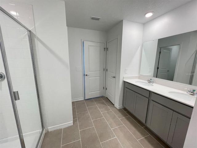 bathroom with vanity, a shower with door, and a textured ceiling