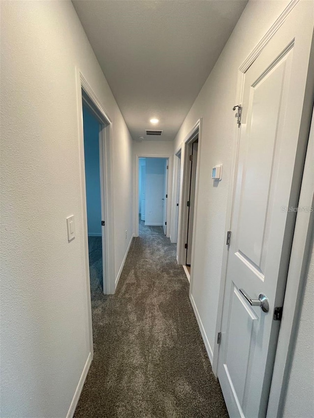 hallway featuring dark carpet