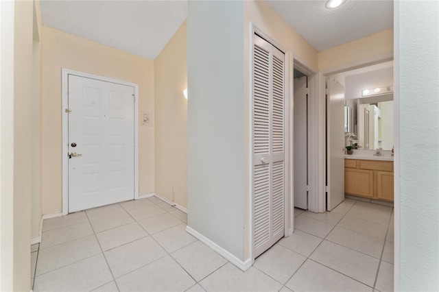 corridor with sink, light tile patterned floors, and a textured ceiling