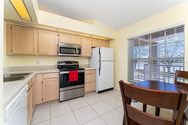 kitchen featuring sink, vaulted ceiling, light tile patterned floors, light brown cabinets, and stainless steel appliances