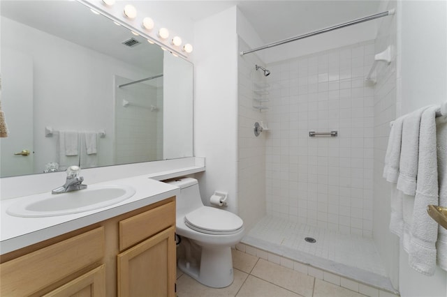 bathroom featuring tile patterned flooring, vanity, toilet, and tiled shower