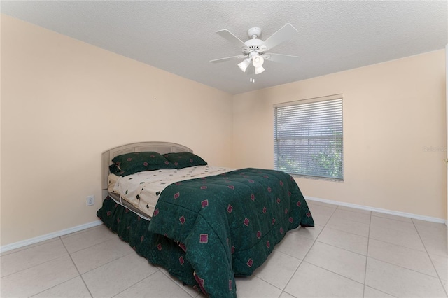 bedroom with ceiling fan, tile patterned floors, and a textured ceiling