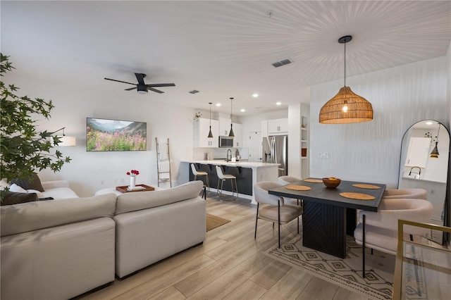 living room with sink, ceiling fan, and light wood-type flooring