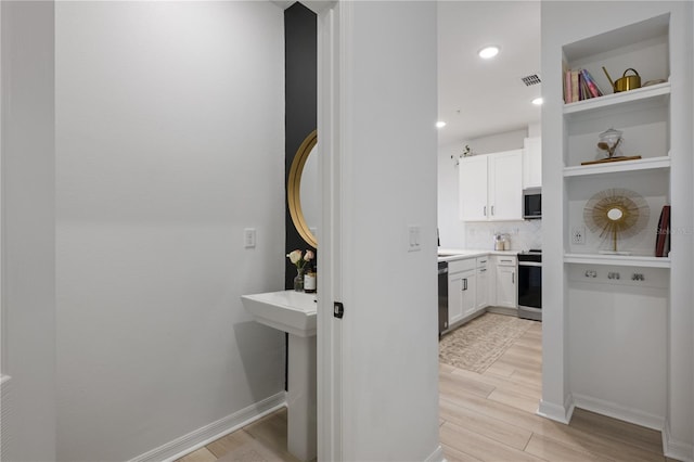 kitchen featuring white cabinetry, tasteful backsplash, appliances with stainless steel finishes, and light hardwood / wood-style flooring