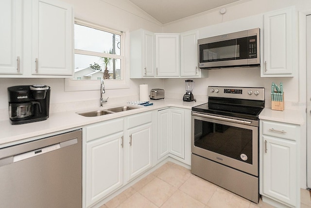 kitchen featuring sink, white cabinetry, stainless steel appliances, light tile patterned flooring, and vaulted ceiling