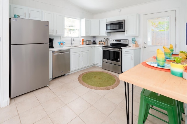 kitchen featuring sink, vaulted ceiling, stainless steel appliances, and white cabinets