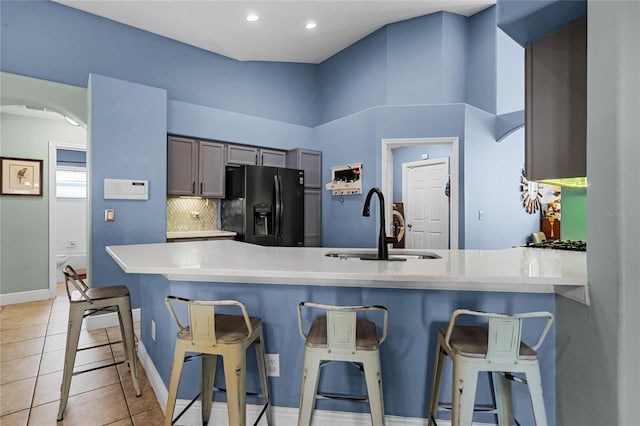 kitchen with black fridge, a breakfast bar, kitchen peninsula, and sink