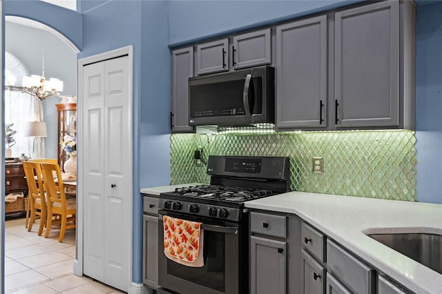 kitchen featuring gas stove, gray cabinetry, backsplash, and light tile patterned floors