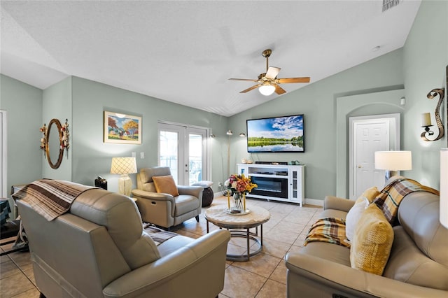 tiled living room with ceiling fan, a fireplace, a textured ceiling, vaulted ceiling, and french doors