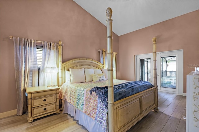 bedroom with access to exterior, vaulted ceiling, and light hardwood / wood-style floors