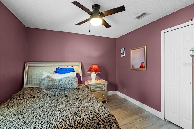 bedroom featuring ceiling fan, a textured ceiling, and light wood-type flooring