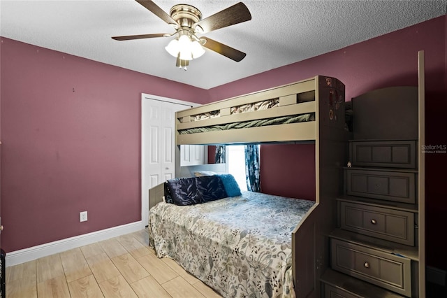 bedroom featuring a closet, ceiling fan, light hardwood / wood-style floors, and a textured ceiling