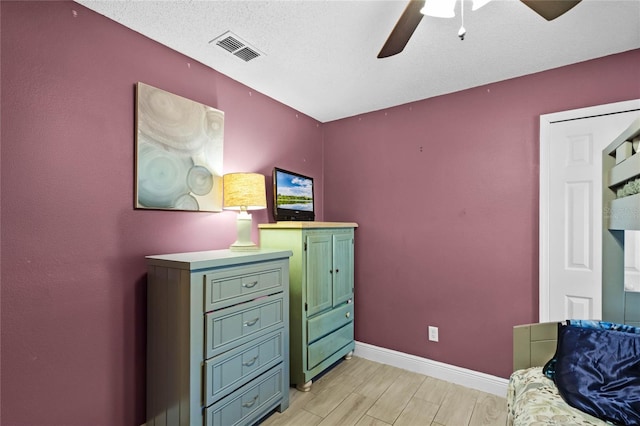 bedroom featuring ceiling fan, light hardwood / wood-style floors, and a textured ceiling