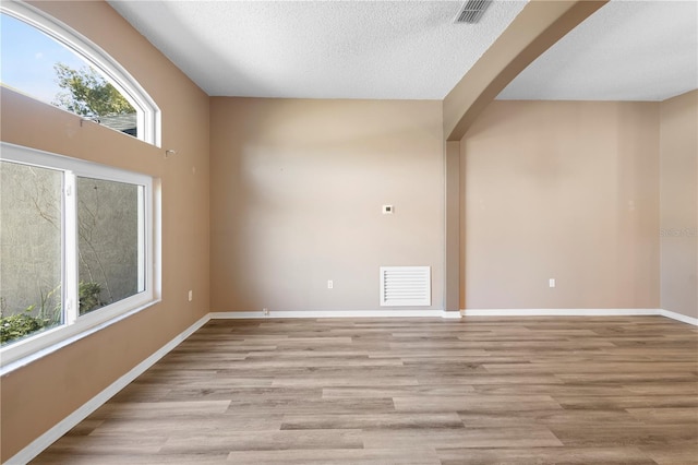 unfurnished room featuring a textured ceiling and light hardwood / wood-style floors