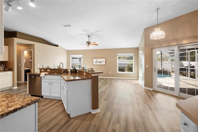 kitchen featuring sink, white cabinets, decorative light fixtures, vaulted ceiling, and stainless steel dishwasher