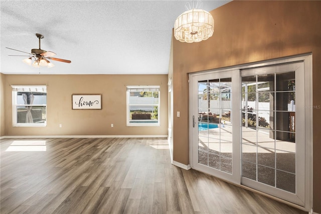 doorway to outside featuring hardwood / wood-style flooring, ceiling fan with notable chandelier, and a textured ceiling