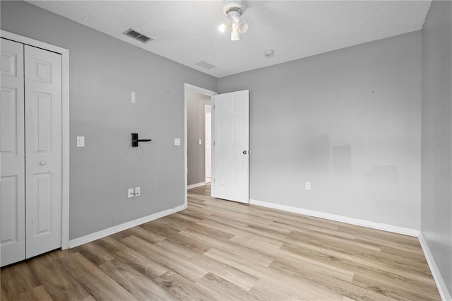 unfurnished bedroom with light hardwood / wood-style floors and a textured ceiling