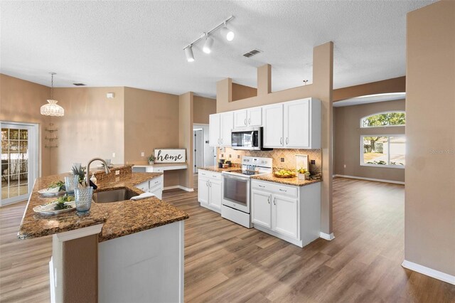 kitchen with pendant lighting, sink, white electric range, white cabinetry, and a kitchen island with sink