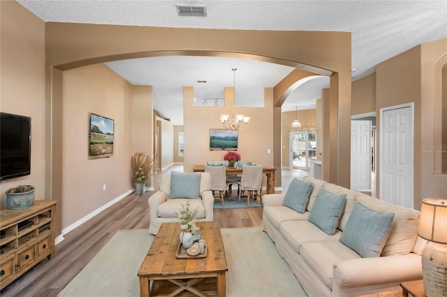 living room featuring wood-type flooring, a chandelier, and a textured ceiling