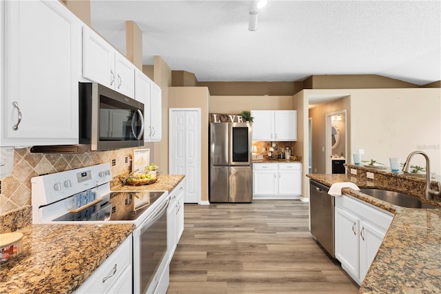 kitchen featuring sink, stone counters, appliances with stainless steel finishes, light hardwood / wood-style floors, and white cabinets