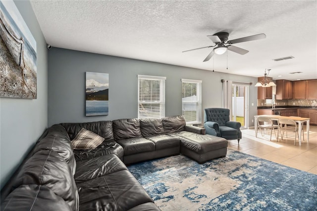 living room featuring a textured ceiling, ceiling fan, and light tile patterned flooring