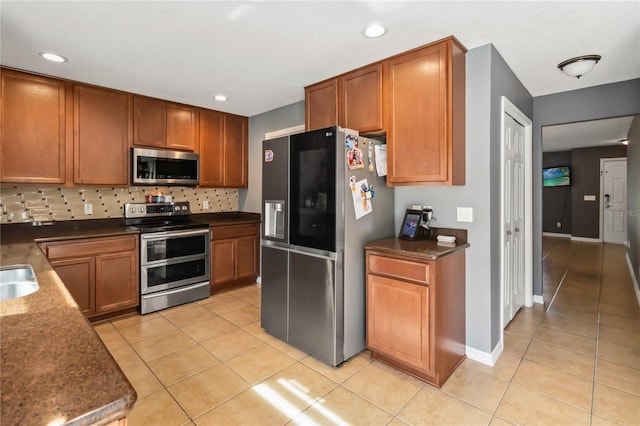 kitchen with tasteful backsplash, light tile patterned floors, and stainless steel appliances