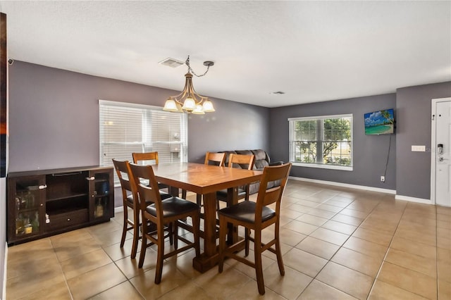 tiled dining room featuring an inviting chandelier