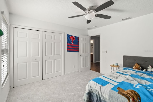 bedroom with multiple windows, light carpet, a closet, and a textured ceiling