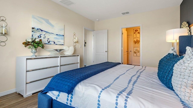 bedroom with connected bathroom and light hardwood / wood-style floors