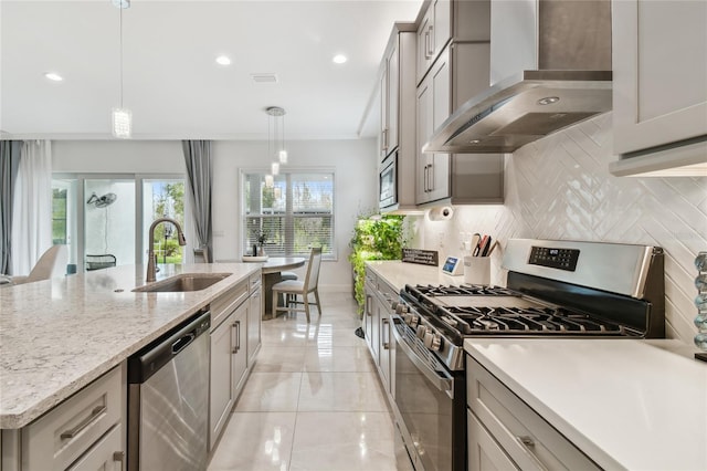 kitchen with appliances with stainless steel finishes, decorative light fixtures, sink, decorative backsplash, and wall chimney exhaust hood