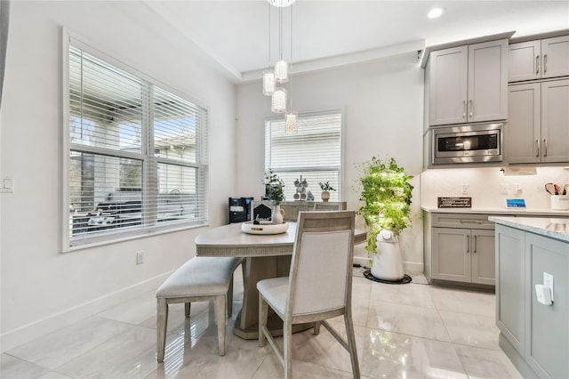 kitchen with pendant lighting, stainless steel microwave, gray cabinets, and tasteful backsplash