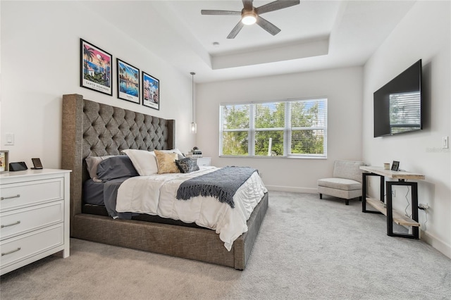 carpeted bedroom with a raised ceiling and ceiling fan