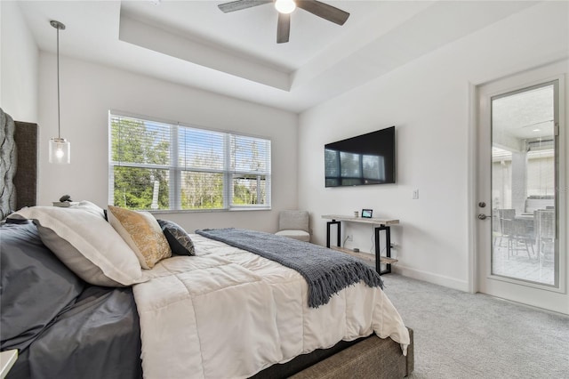 carpeted bedroom featuring access to outside, ceiling fan, and a tray ceiling