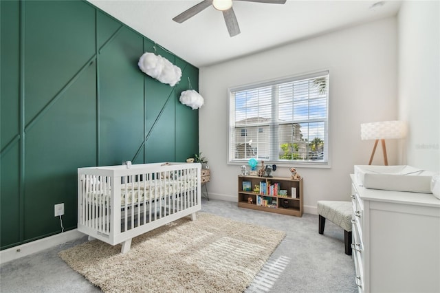 carpeted bedroom with a nursery area and ceiling fan