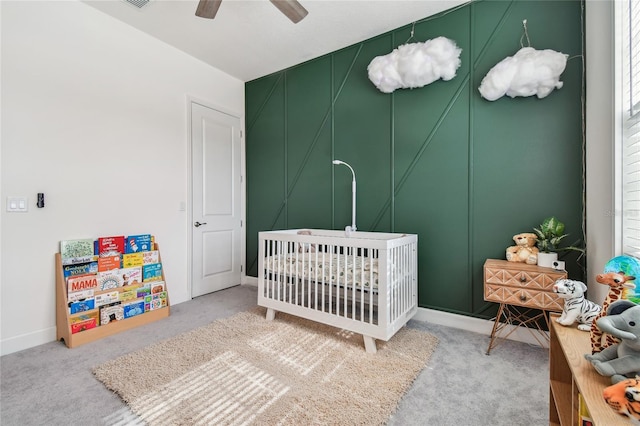 carpeted bedroom featuring ceiling fan and a crib