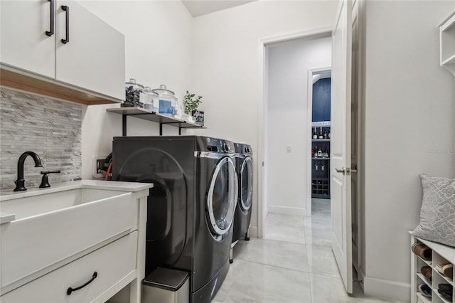 laundry area with cabinets, washing machine and dryer, sink, and light tile patterned floors