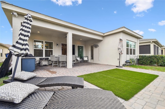 back of property featuring ceiling fan and a patio area