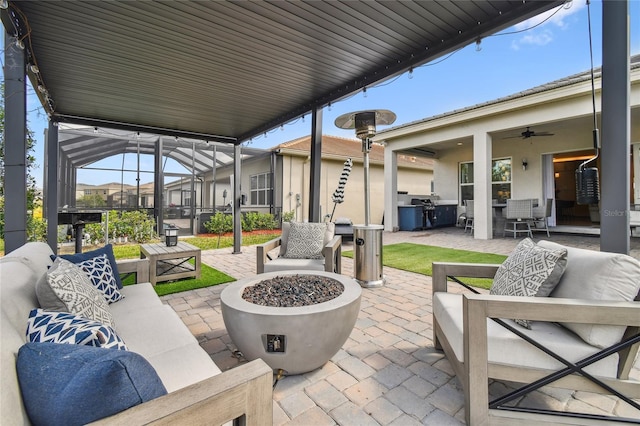 view of patio featuring a grill, an outdoor living space with a fire pit, ceiling fan, and glass enclosure