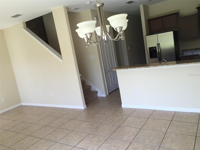 kitchen with stone counters, dark brown cabinets, light tile patterned floors, and stainless steel fridge with ice dispenser