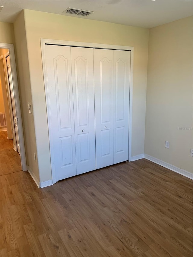 unfurnished bedroom with hardwood / wood-style flooring and a closet