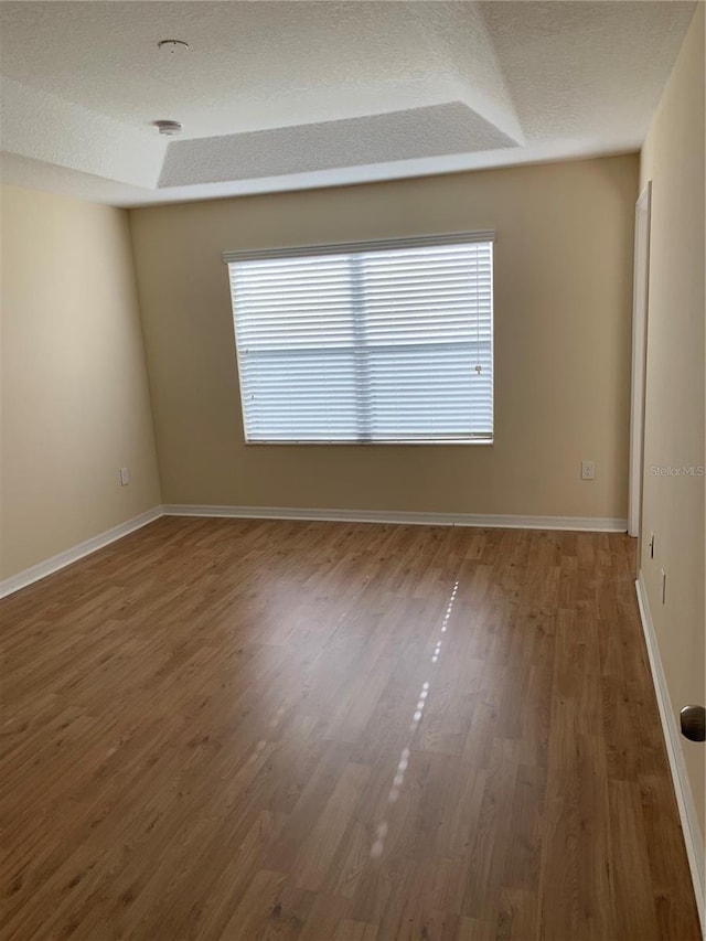 unfurnished room featuring a healthy amount of sunlight, wood-type flooring, and a textured ceiling