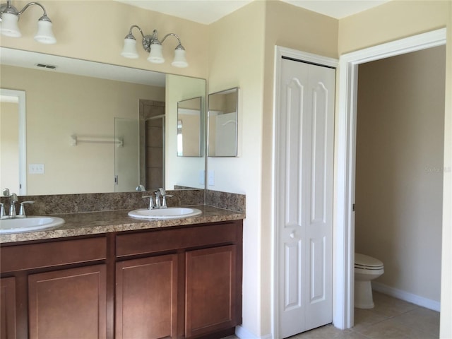 bathroom with tile patterned flooring, vanity, a shower with door, and toilet