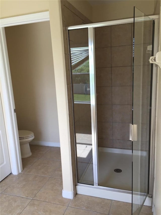 bathroom featuring tile patterned floors, toilet, and an enclosed shower