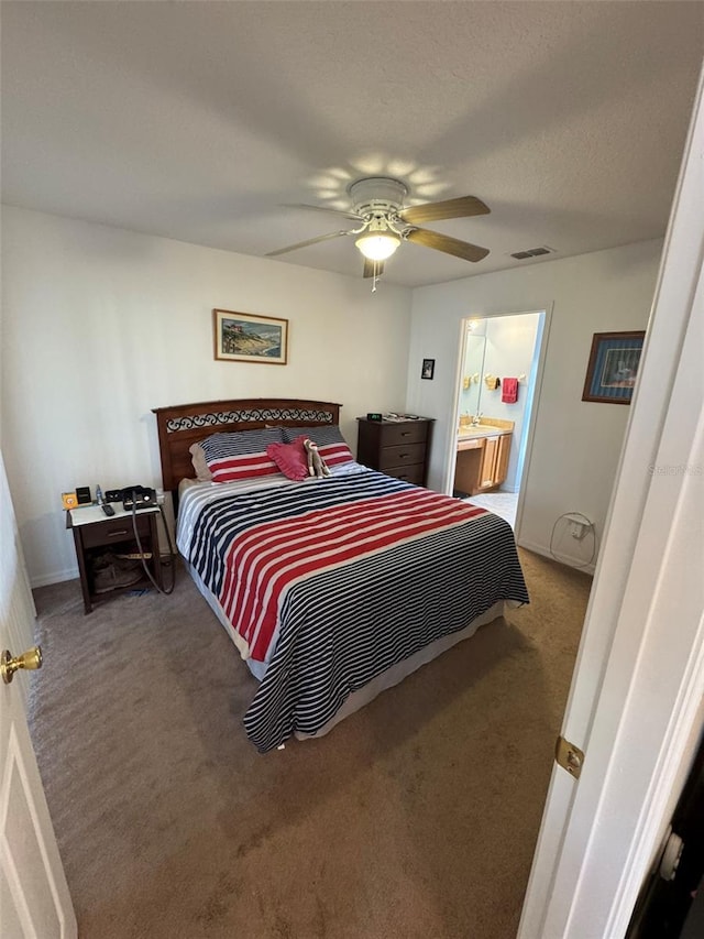 bedroom featuring ceiling fan, ensuite bath, a textured ceiling, and carpet flooring