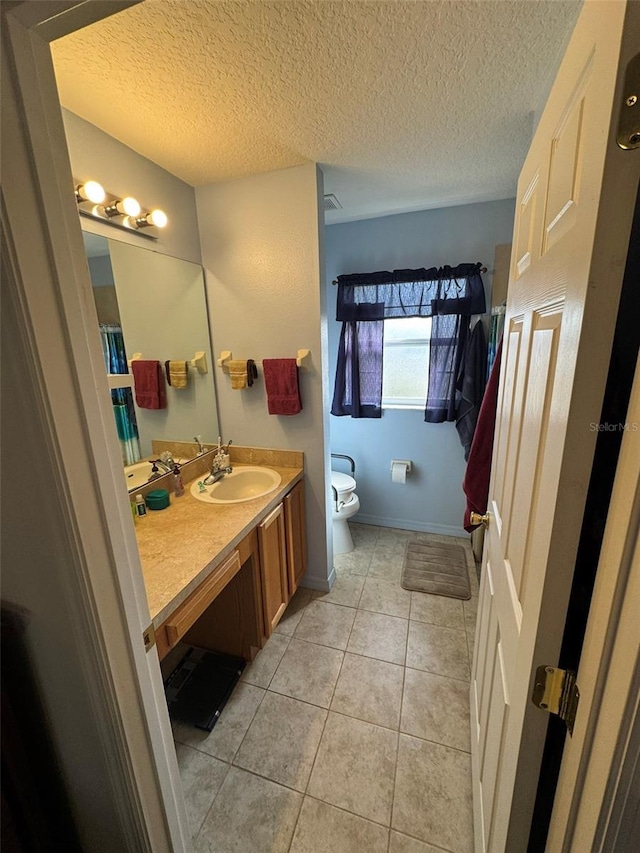 bathroom with tile patterned flooring, vanity, a textured ceiling, and toilet