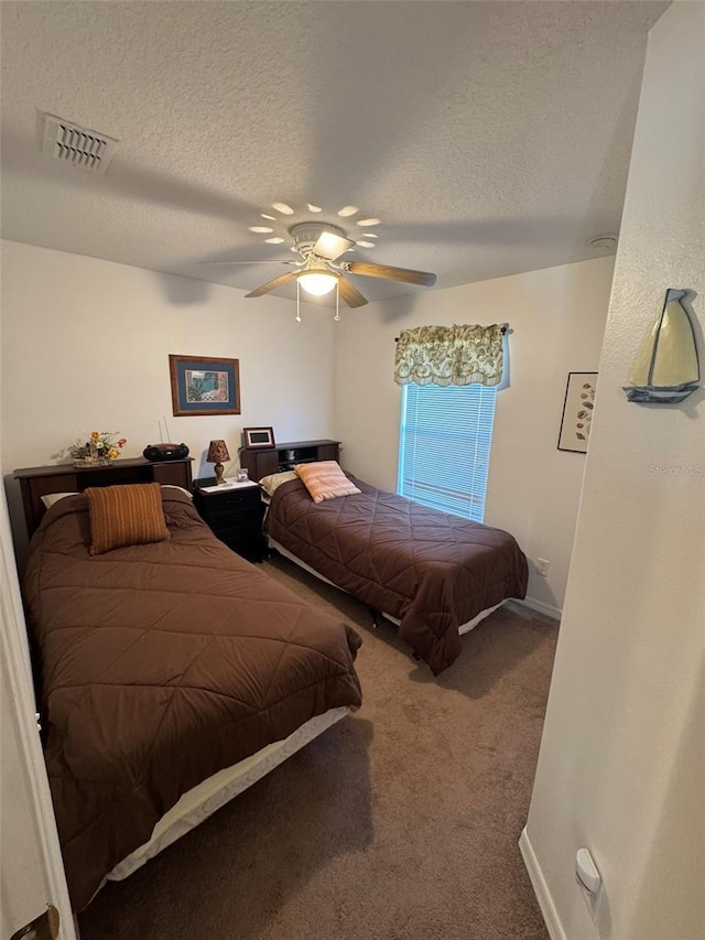 carpeted bedroom with ceiling fan and a textured ceiling