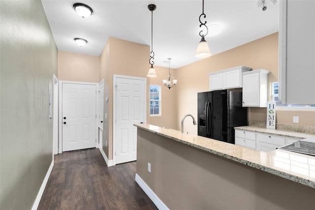 kitchen with dark wood-type flooring, black fridge, white cabinetry, hanging light fixtures, and light stone countertops