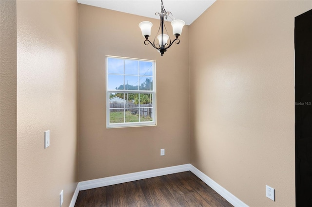 spare room featuring dark hardwood / wood-style flooring and a chandelier