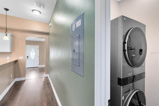 interior space featuring stacked washer / drying machine, electric panel, and dark hardwood / wood-style floors