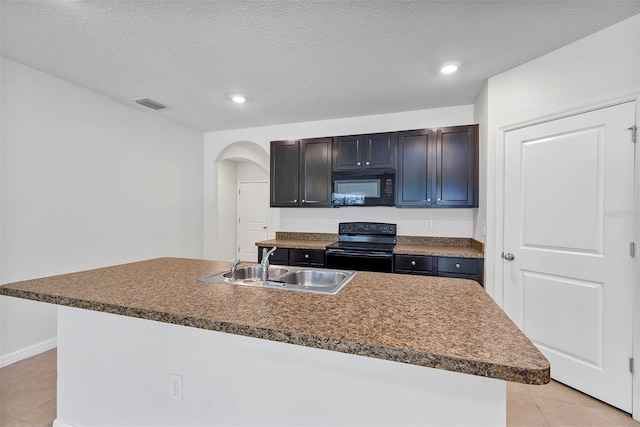 kitchen with sink, light tile patterned floors, black appliances, and a center island with sink